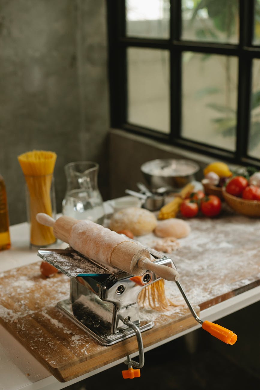 manual pasta machine with dough on rolling pin