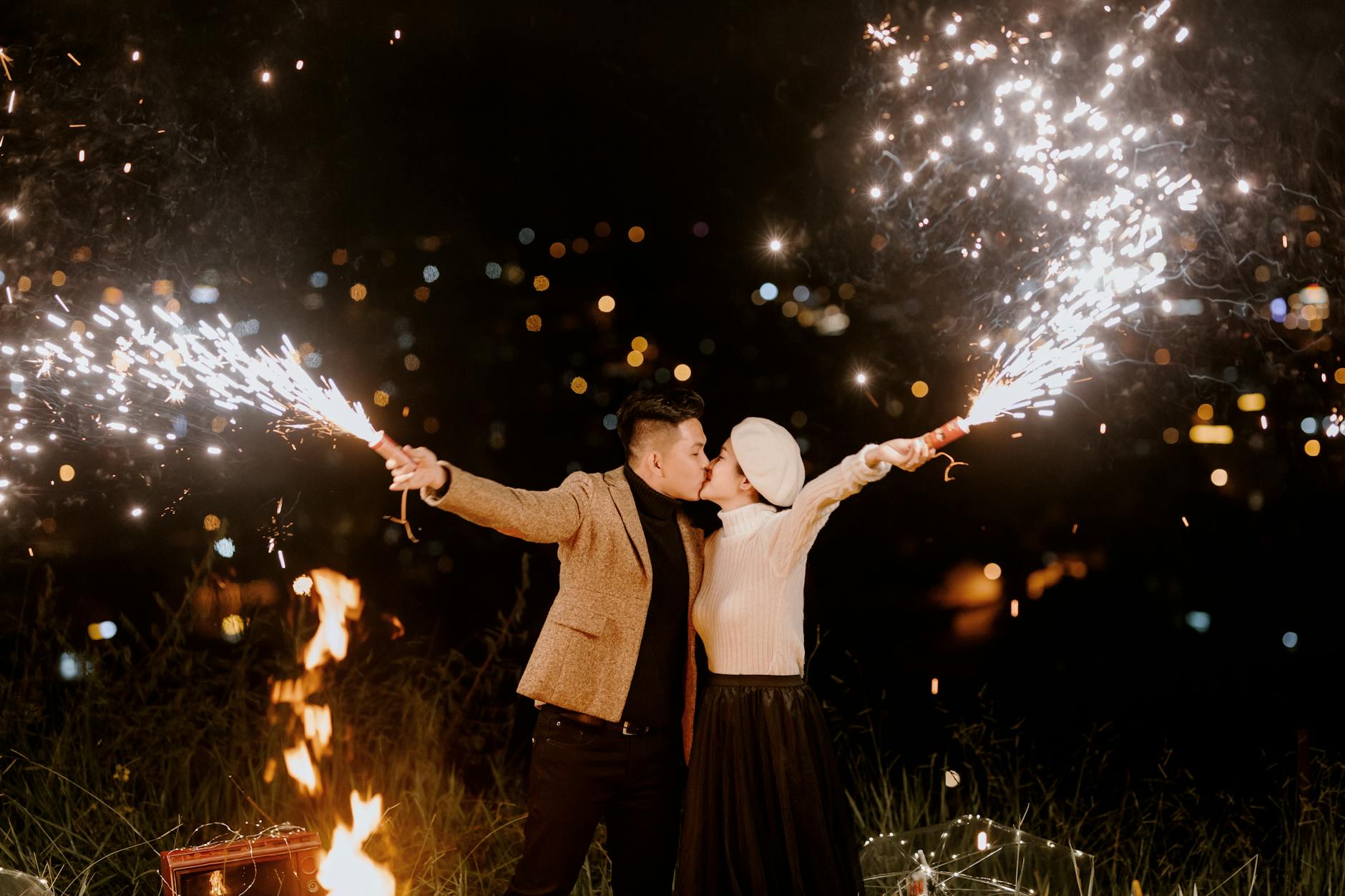 stylish couple with fireworks at night