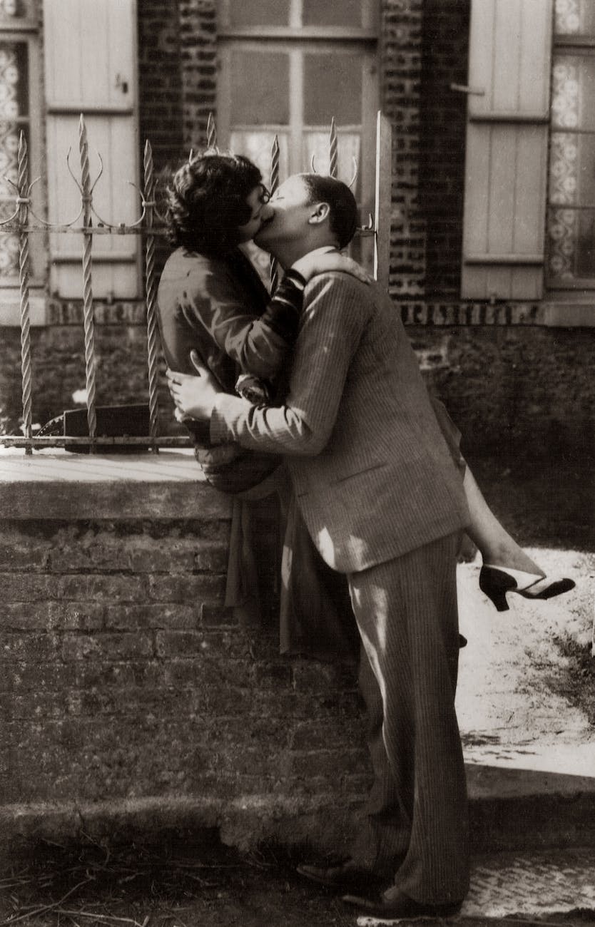 man and woman kissing on sidewalk