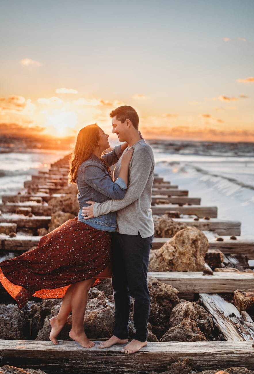 romantic couple embracing on wooden pier at sunset