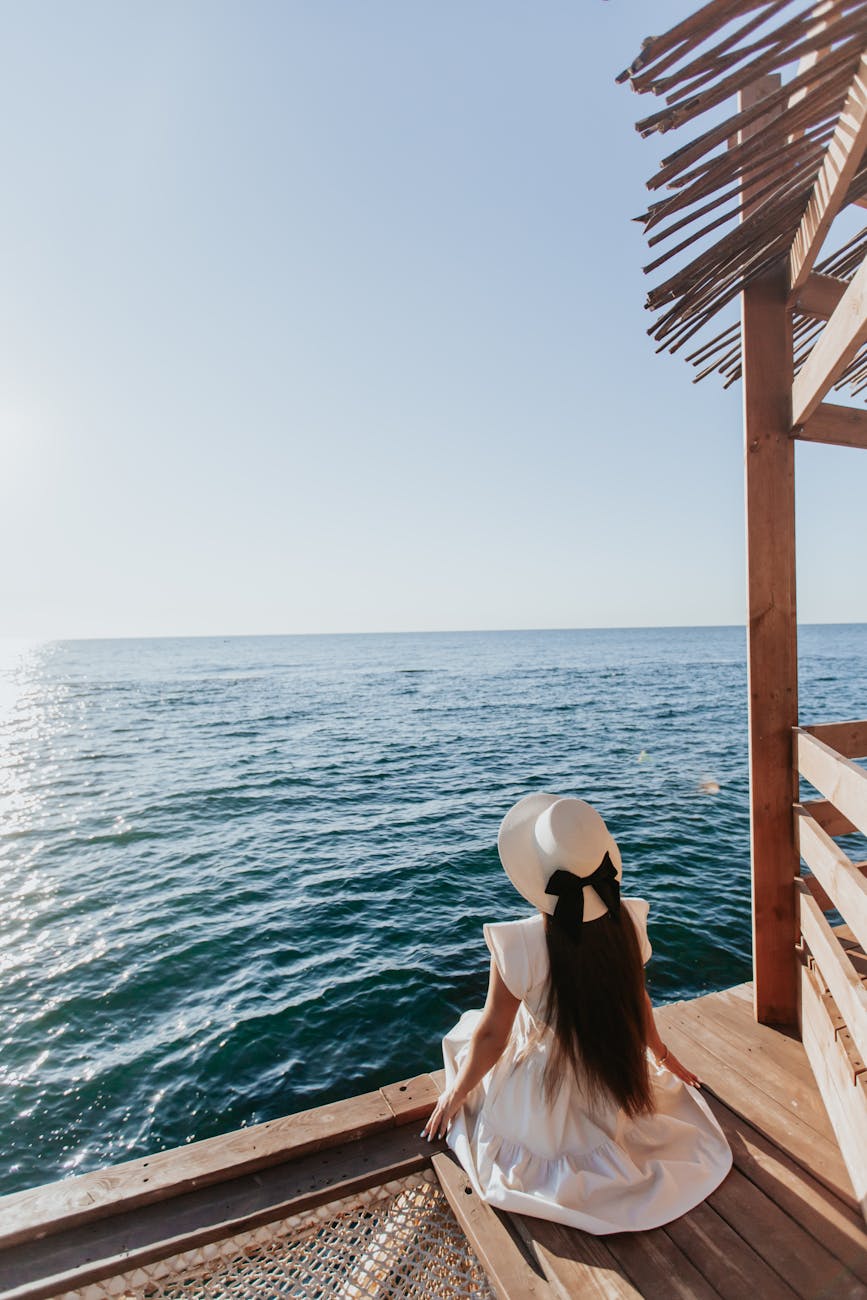 anonymous young lady admiring sea from wooden boardwalk