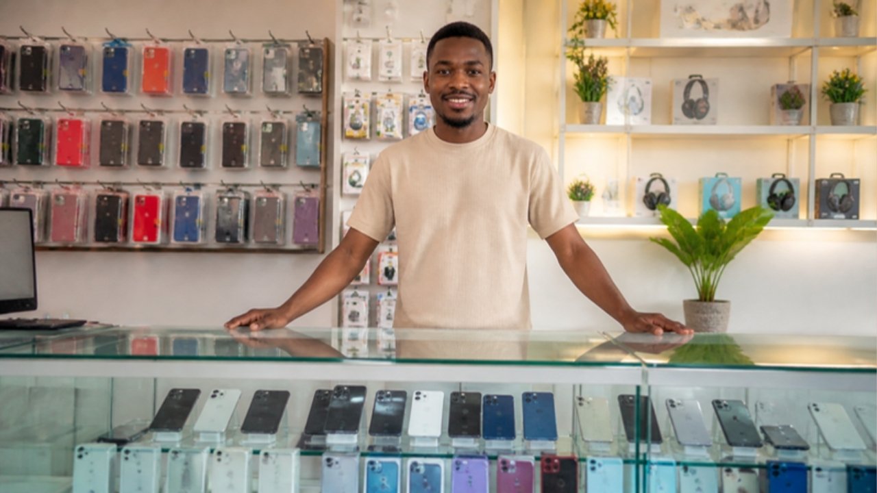 Ghanaian entrepreneur behind the glass counter of a phone and accessories shop